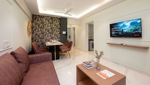 Een moderne woonkamer met een bank, een salontafel en een flatscreen televisie aan de muur.