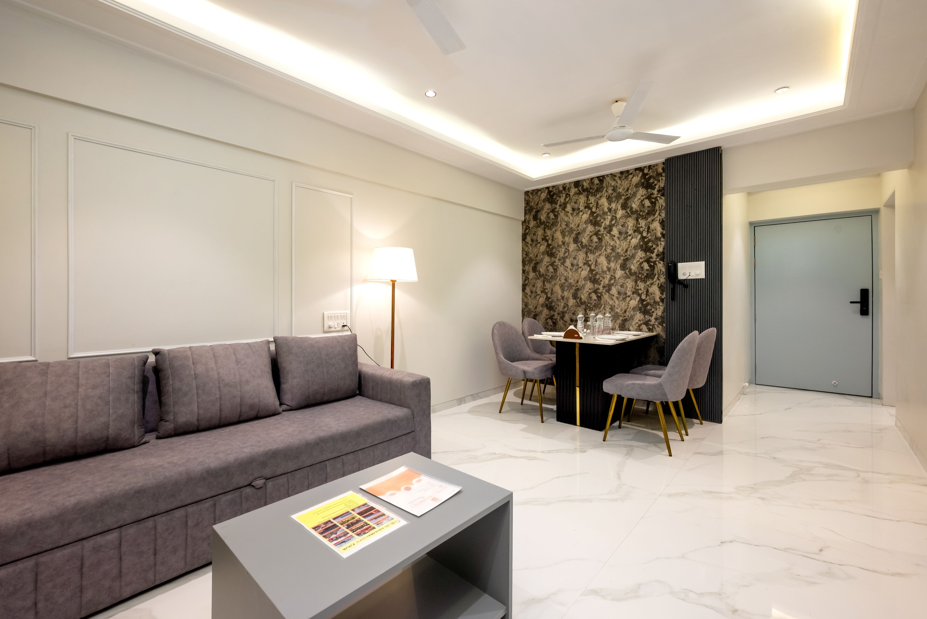 Un salon moderne avec un canapé gris, une petite table basse et un coin repas comprenant une table et des chaises.