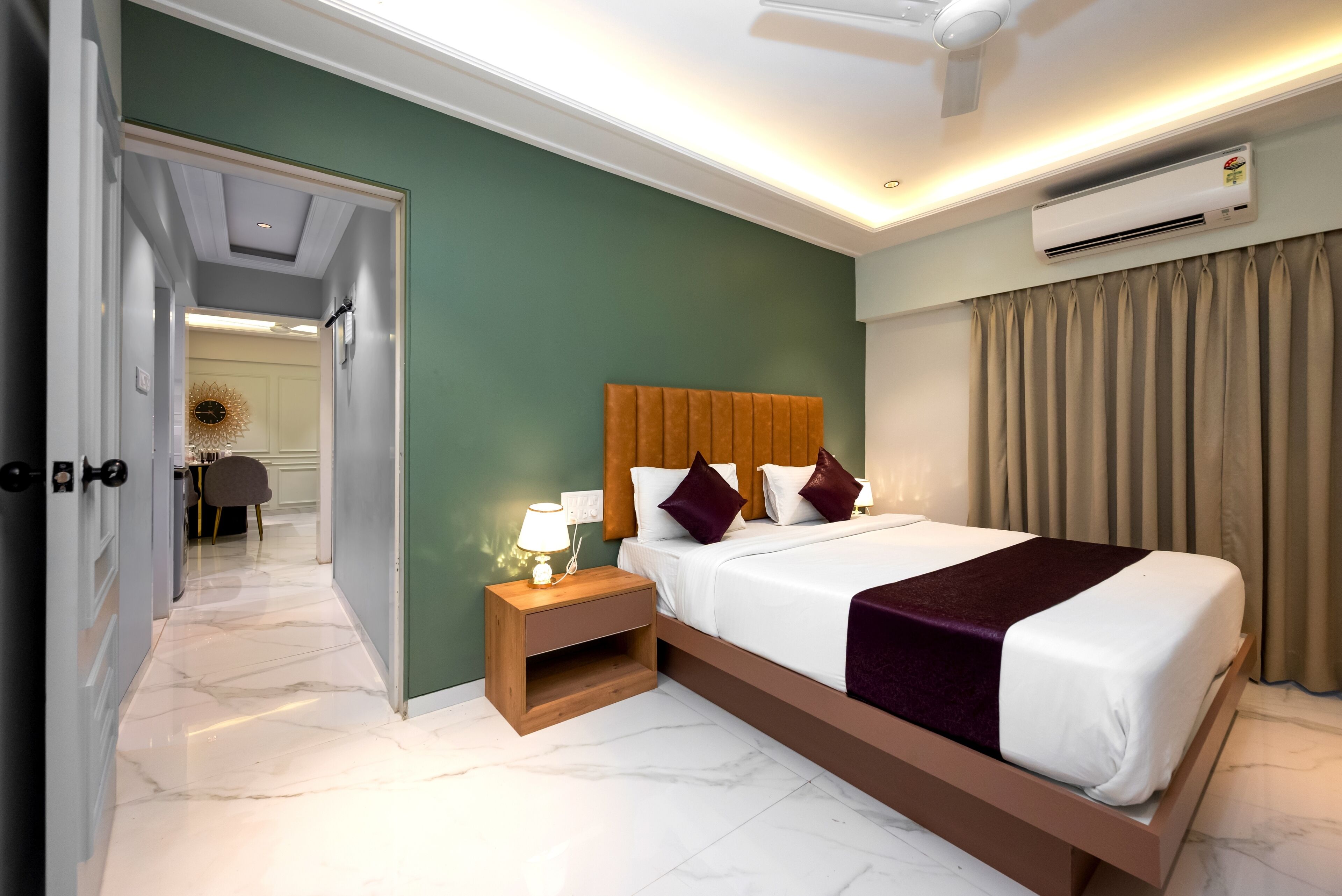 A hotel room with a bed, bedside table, and an air conditioning unit.