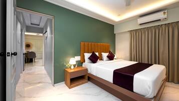 A hotel room with a bed, bedside table, and an air conditioning unit.
