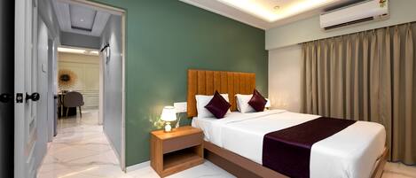 A hotel room with a bed, bedside table, and an air conditioning unit.