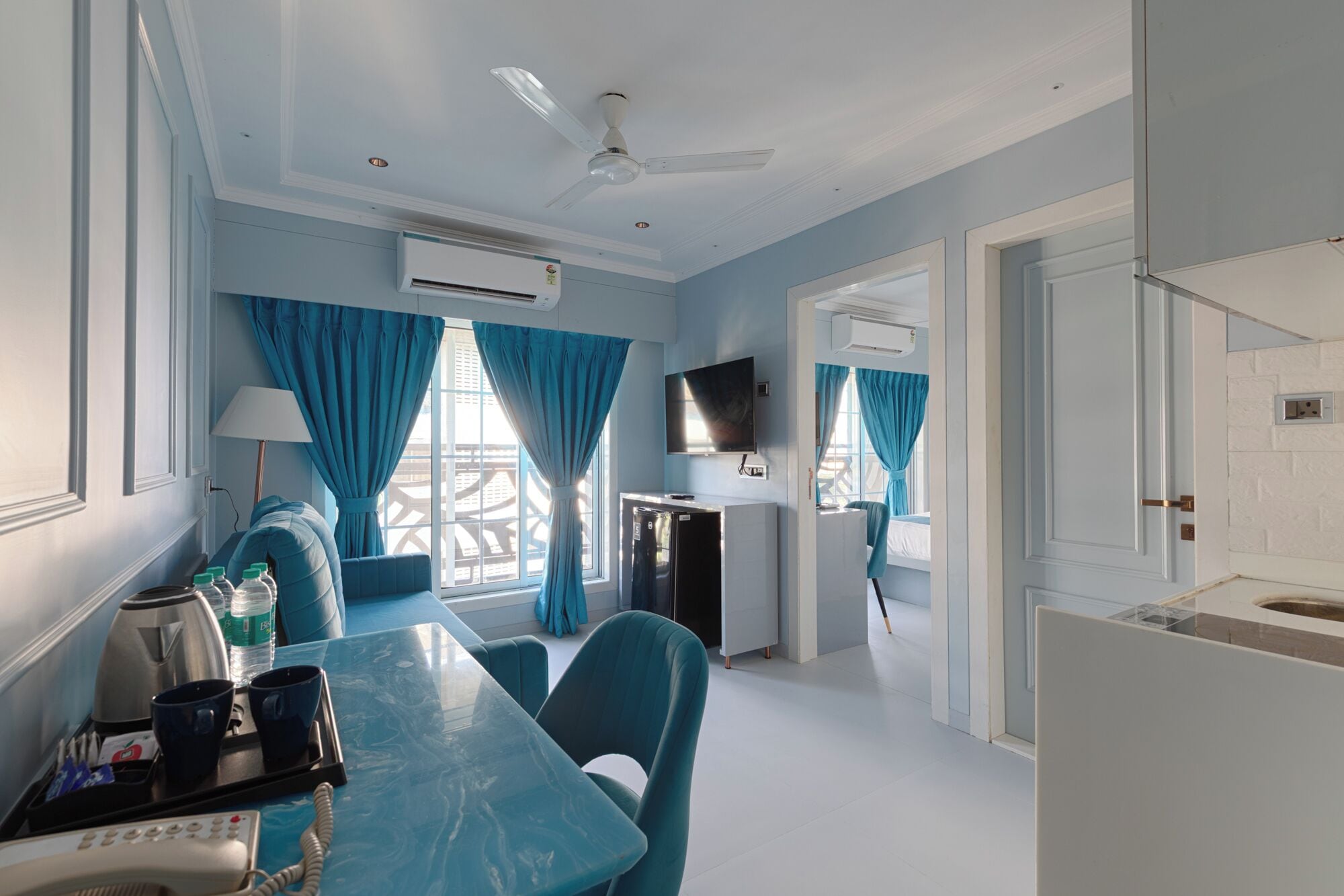 A modern hotel room with a dining area, a TV, and an air conditioning unit.