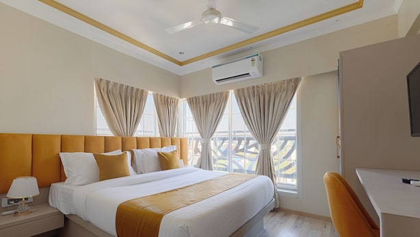 Een hotelkamer met een bed, een bureau, een airconditioner en uitzicht op buiten.