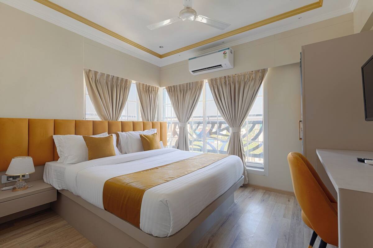 Ein Hotelzimmer mit Bett, Schreibtisch, Klimaanlage und Blick ins Freie.