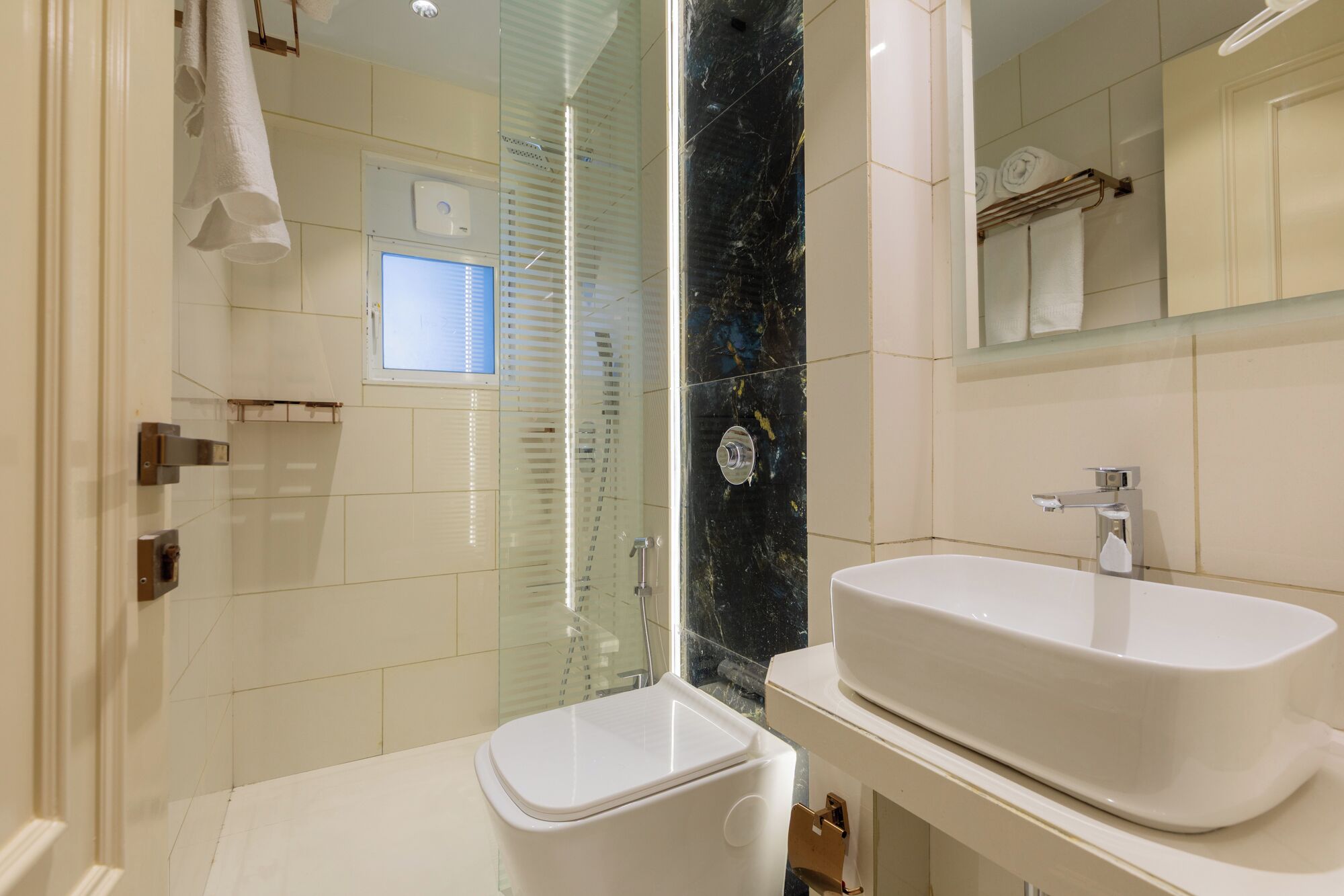 A modern bathroom with a glass shower enclosure, a white toilet, and a large white sink.