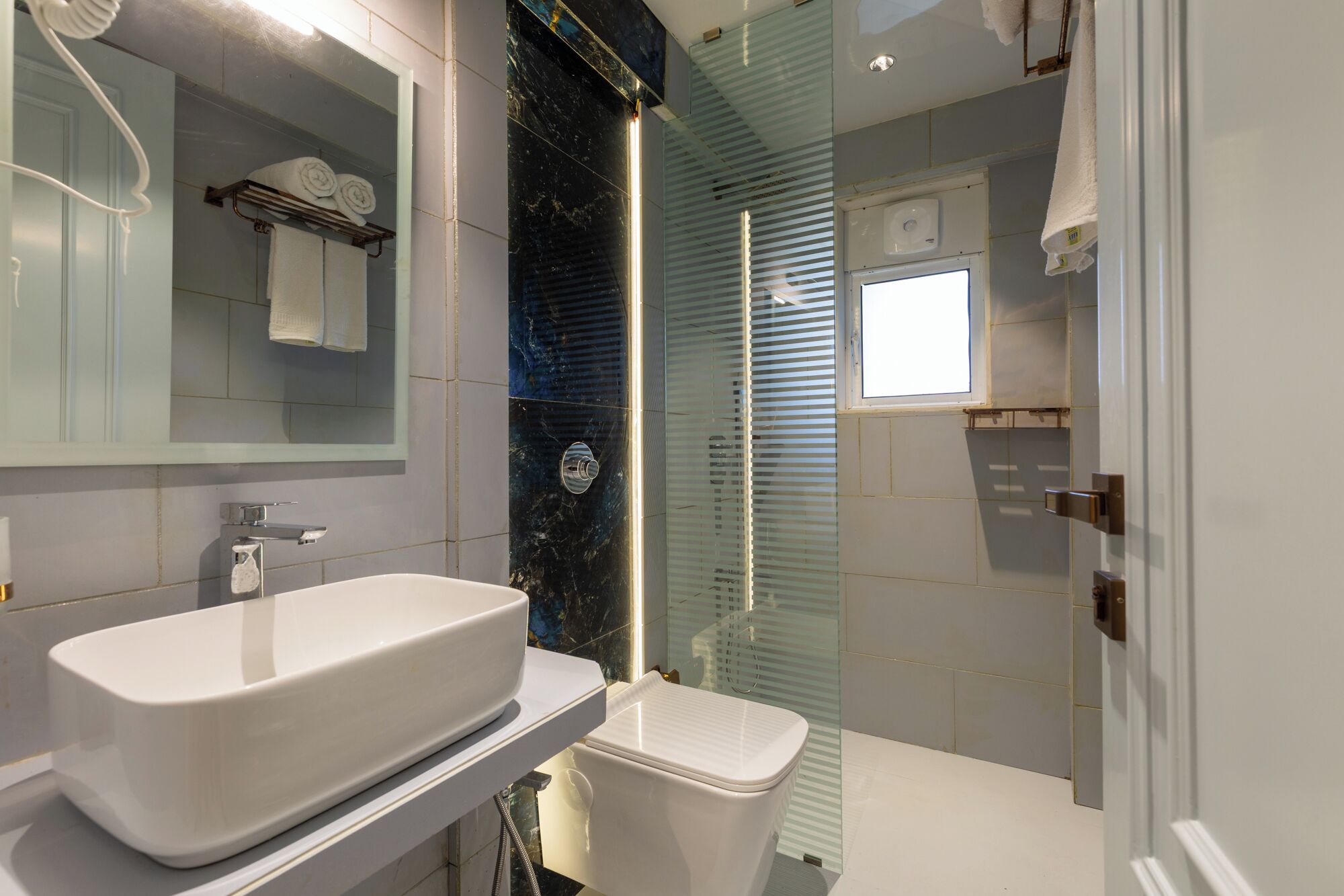 A modern bathroom with a white sink, a toilet, and a glass shower enclosure.