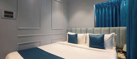 A neatly made bed with a blue and white bedspread, a tufted headboard, and a bedside telephone.
