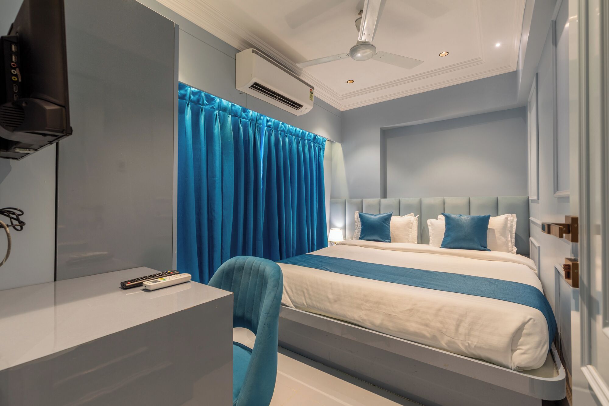 A modern hotel room with a bed, a desk, and a chair.