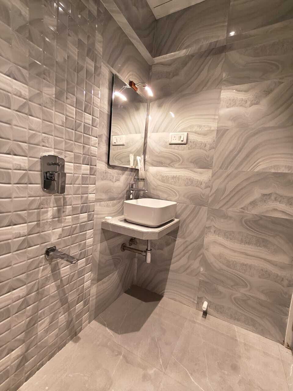 A bathroom with a marble wall, a sink, and a mirror.
