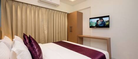 Une chambre d’hôtel moderne équipée d’un lit, de rideaux, d’un appareil de climatisation, d’une télévision et d’une armoire en bois.