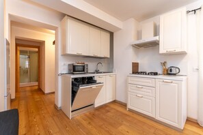A compact kitchen with white cabinets, a built-in oven, a microwave, and a gas stove.