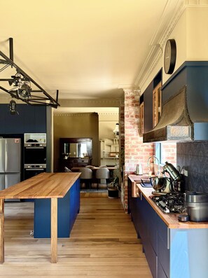 A modern kitchen with a wooden island, built-in appliances, and a brick accent wall.