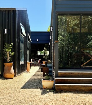 A modern building with large windows and a gravel pathway leading to a seating area.