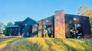 Een modern huis met een grote schoorsteen, een schuin dak en een verzorgd gazon.