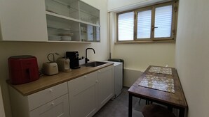 Ett litet kök med en diskho, en kaffemaskin, en brödrost och en röd apparat på bänkskivan.