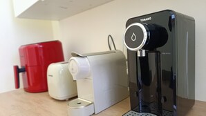 Ett kök med en kaffebryggare, en brödrost och en vattenautomat på en bänkskiva av trä.