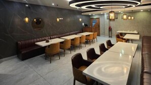 Un espace repas moderne avec une table ronde centrale, des banquettes disposées tout autour et un long comptoir.