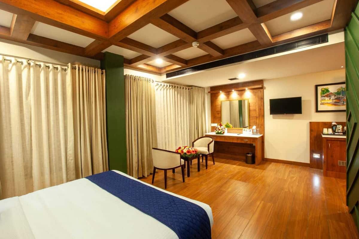 A hotel room with a bed, a desk, a chair, a TV, and a bathroom.