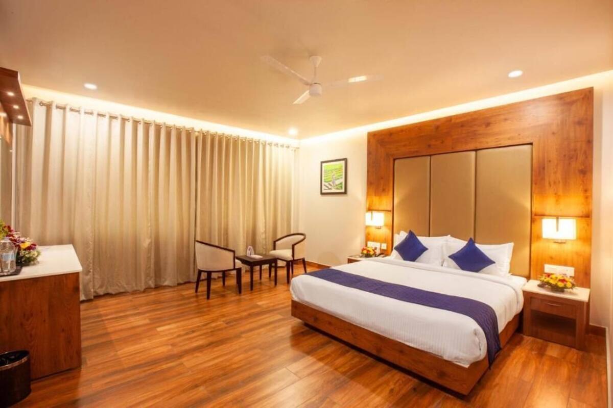 A hotel room with a large bed, a desk, a chair, a desk lamp, and a ceiling fan.