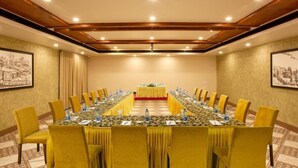 Une salle de conférence avec une longue table, des chaises jaunes et une moquette rouge.