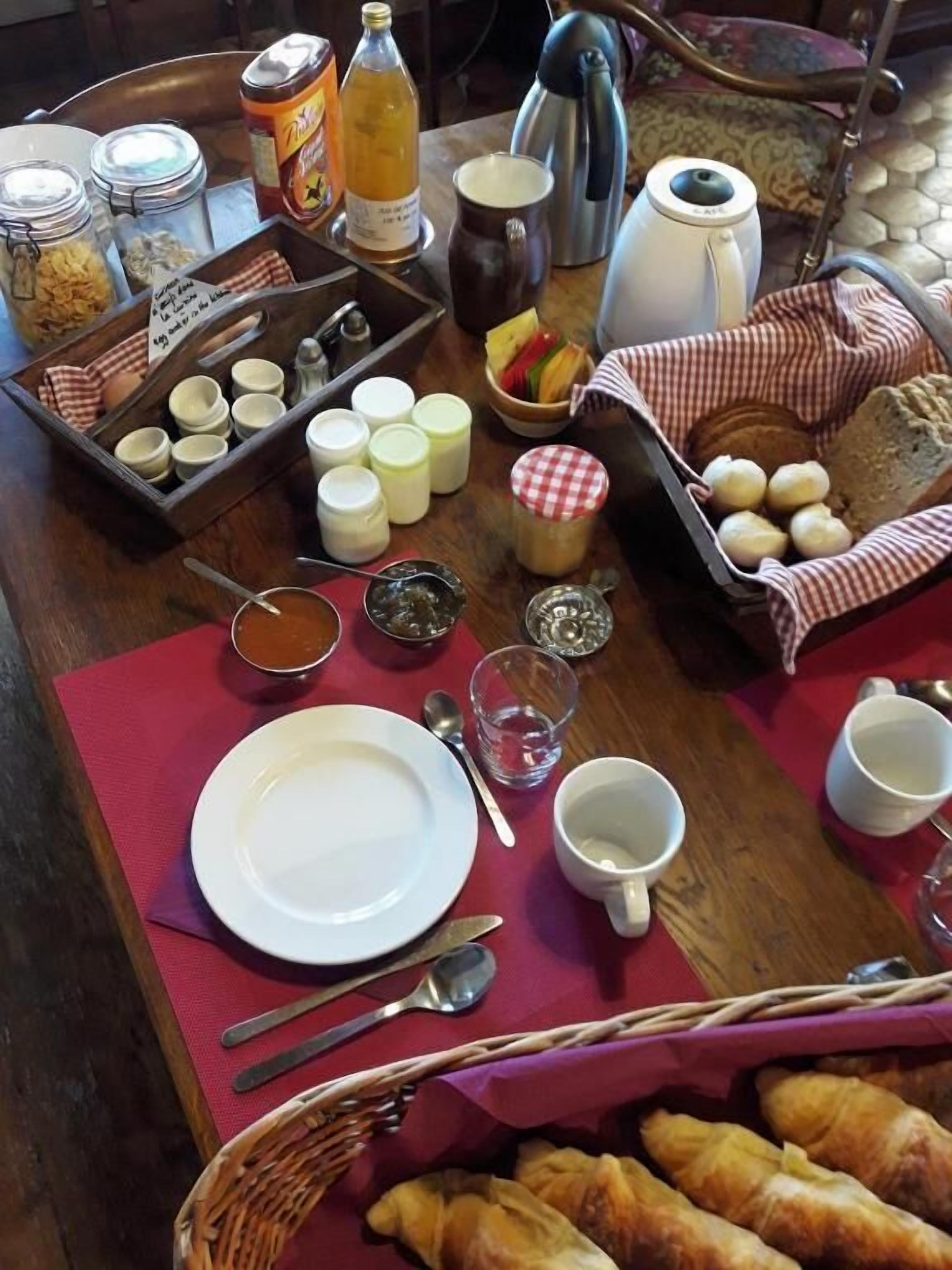 Ein Esstisch mit verschiedenen Speisen, Geschirr und einer Kaffeemaschine.