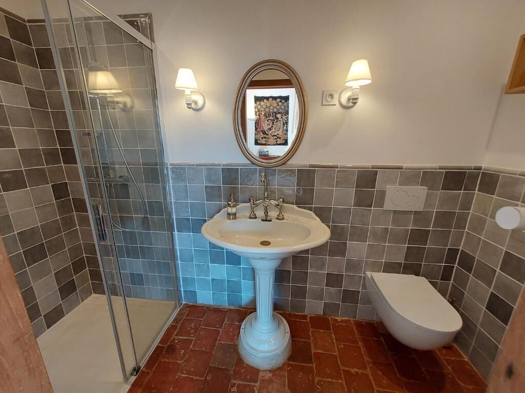 Une salle de bain avec un lavabo sur colonne, des toilettes et une douche à parois de verre.