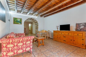 Ein Wohnzimmer mit einer Couch, einem Holzesstisch, einem Fernseher und einem Steingewölbe.