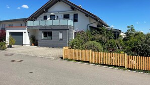 Ett tvåvåningshus med ett garage, en balkong och ett trästaket.