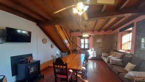 Ein gemütliches Wohnzimmer mit einem Holzesstisch, einem Kamin, einer Couch und einem an der Wand montierten Fernseher.