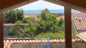 A view from a room with a sloped ceiling, looking out to a coastal area with terracotta roofs and greenery. - La Venelle de Cali - Large Home with 3 Separate Units (Île-d'Aix)