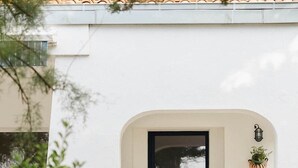 A white building with a black-framed door, a small potted plant, and a lantern on the wall. - Kallisté - Stunning Oceanview Villa (Île-d'Aix)