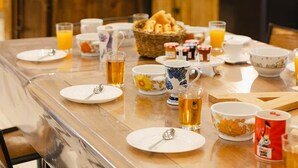 A breakfast setting with a table set for four, including plates, cups, and a basket of bread. - Kallisté - Stunning Oceanview Villa (Île-d'Aix)