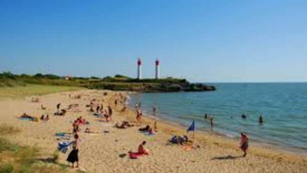 A beach with people sunbathing and swimming, a lighthouse in the background, and a clear sky. - La Léinade - Spacious Family Villa (Île-d'Aix)