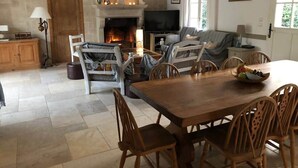 A cozy living room with a fireplace, a dining area, and a television. - La Léinade - Spacious Family Villa (Île-d'Aix)