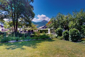 A residential area with houses, a grassy lawn, and a mountain in the background. - Vacation apt. Verena in Garmisch – stylish, central, and with green garden oasis (Garmisch-Partenkirchen)