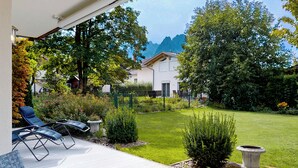 Un patio con mobiliario exterior, un césped cuidado y vistas a una cadena montañosa.