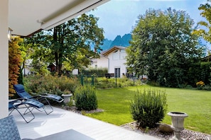 A patio with outdoor furniture, a well-maintained lawn, and a view of a mountain range. - Vacation apt. Verena in Garmisch – stylish, central, and with green garden oasis (Garmisch-Partenkirchen)