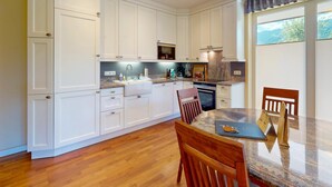Una cocina moderna con armarios blancos, encimera de granito y comedor con mesa y sillas.