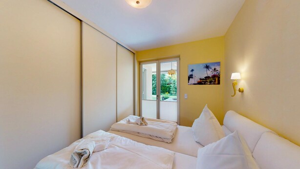 Una habitación de hotel con dos camas, una puerta corredera que da a un balcón y un cuadro en la pared.