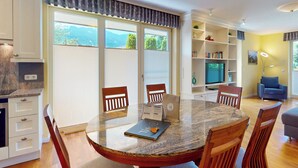 Una sala de estar moderna con una mesa de comedor, sillas, una estantería y un televisor.