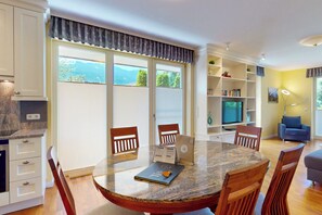 A modern living room with a dining table, chairs, a bookshelf, and a television. - Vacation apt. Verena in Garmisch – stylish, central, and with green garden oasis (Garmisch-Partenkirchen)