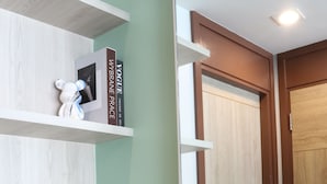 A modern bathroom with a wooden vanity, a large mirror, and shelves with toiletries. - J The Park Condotel (Hat Yai)