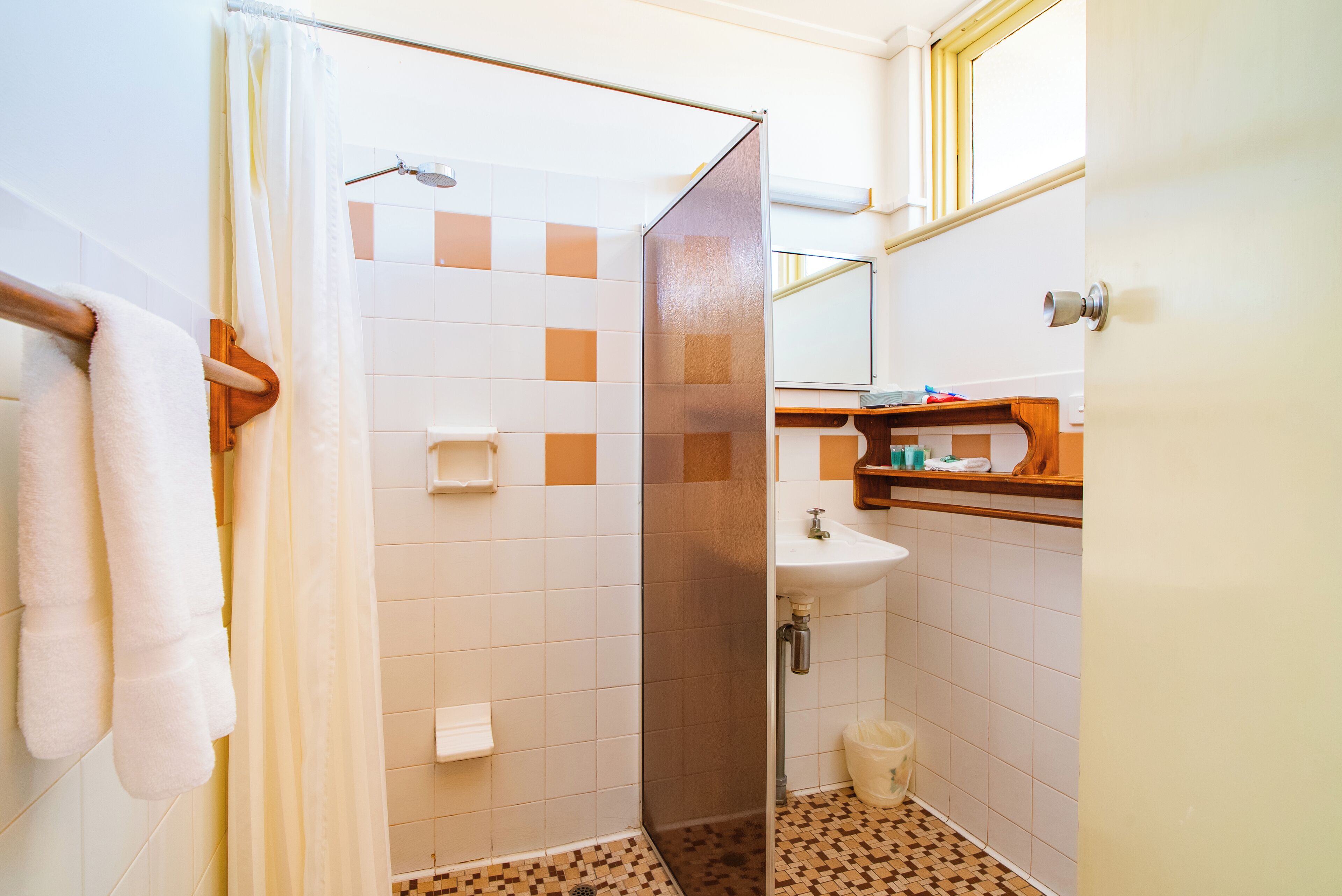 A bathroom with a shower, a sink, and a mirror.