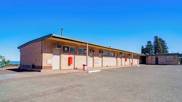 A single-story brick building with a flat roof, a covered parking area, and a clear blue sky.