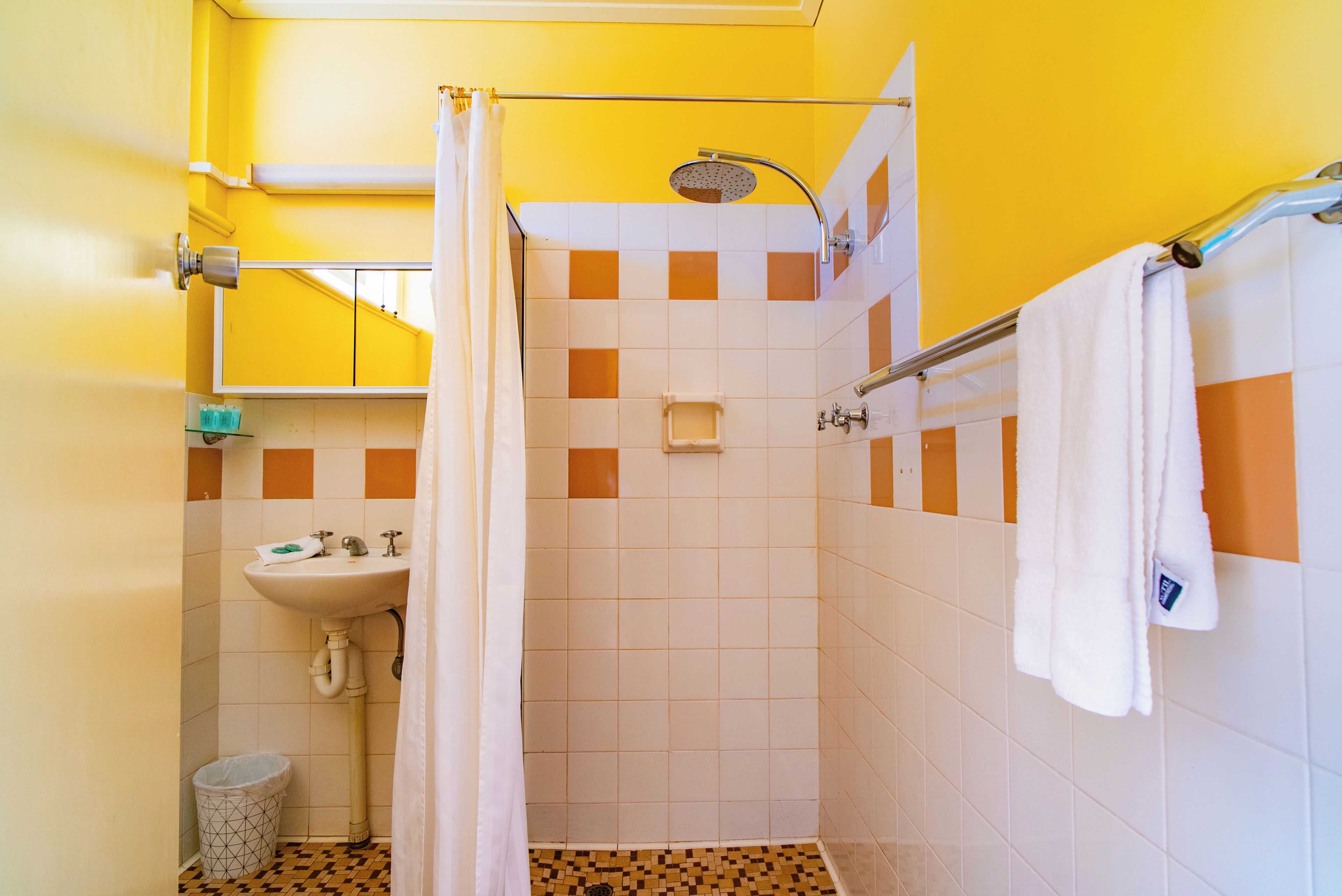 A bathroom with a shower, sink, and a towel rack.