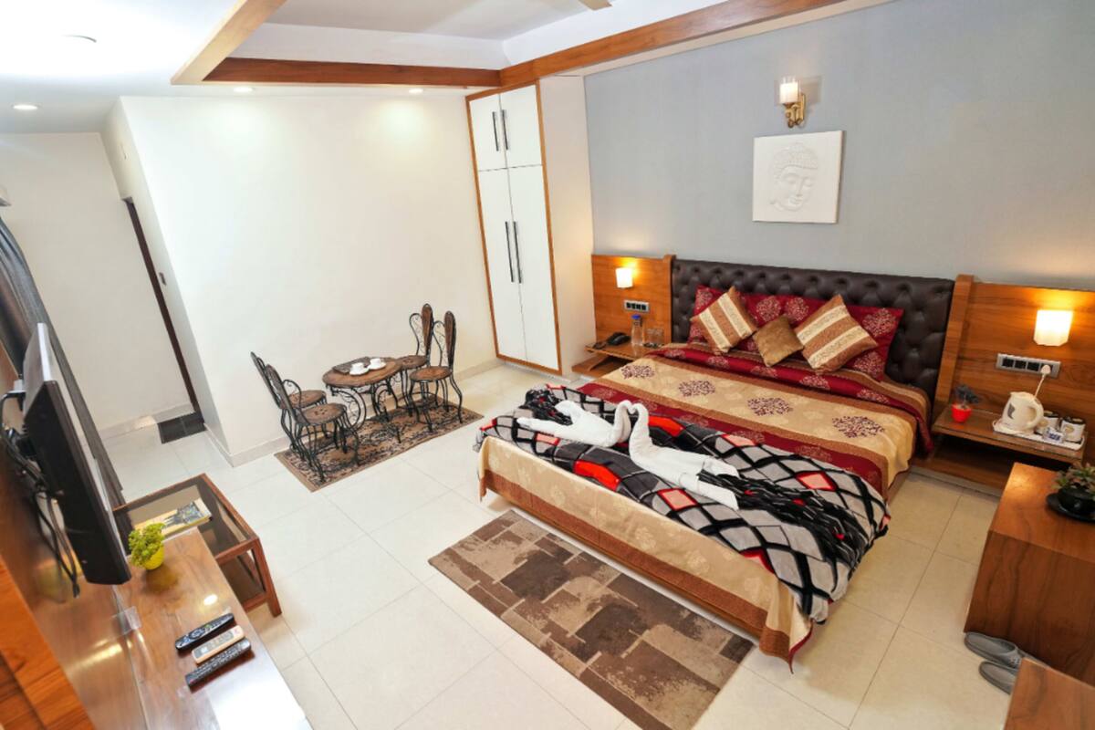 A modern hotel room with a large bed, a desk, a chair, and a TV.