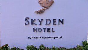 Schild für das Skyden Hotel mit Vogel-Logo und Schriftzug, der angibt, dass es von Amayra Industries Pvt Ltd. betrieben wird.