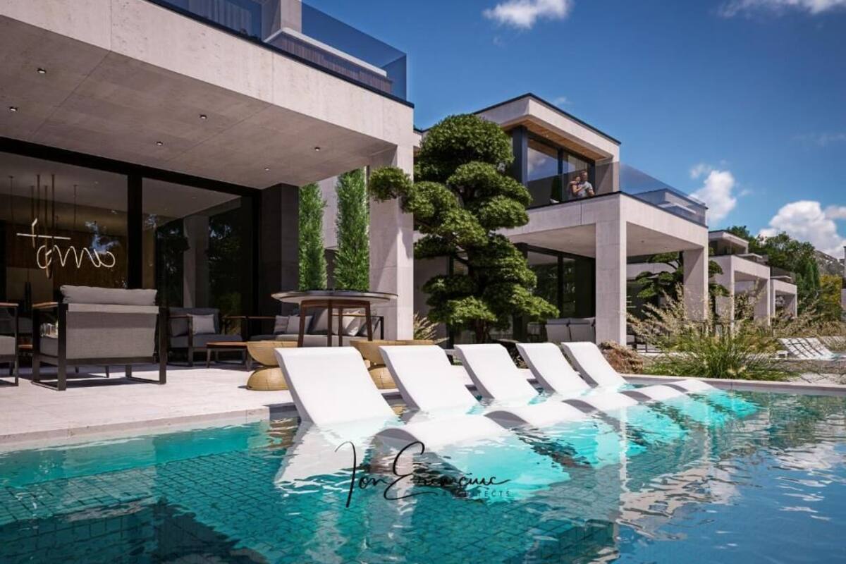 Un espace moderne aménagé au bord de la piscine, avec des chaises longues, une piscine et un bâtiment doté de grandes fenêtres et d'une enseigne au néon.