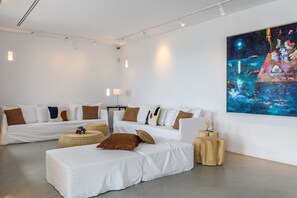 A modern hotel room with a large painting, a sofa set, and a small wooden table. - Villa Atlante with private pool - My Rental Homes (Mykonos)