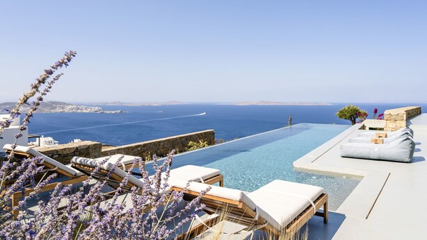 Área da piscina com espreguiçadeiras e vista para o mar.